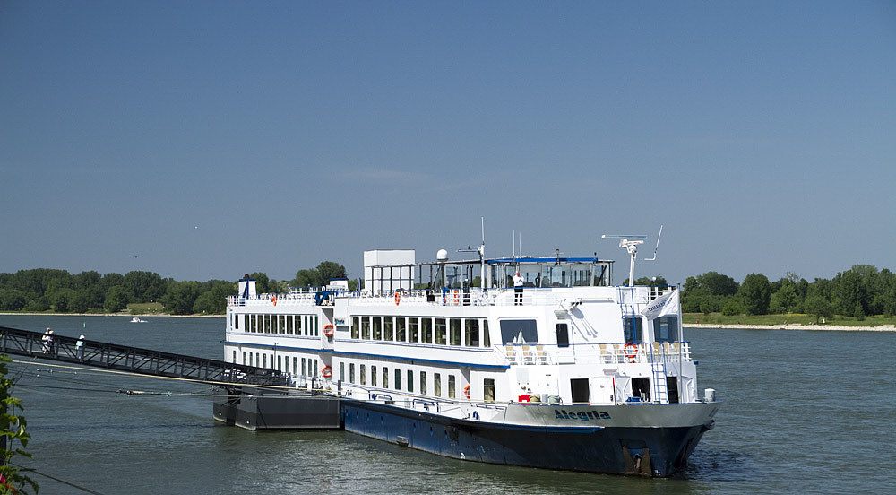 River cruise ship Alegria moored at a floating landing stage with a gangway to shore